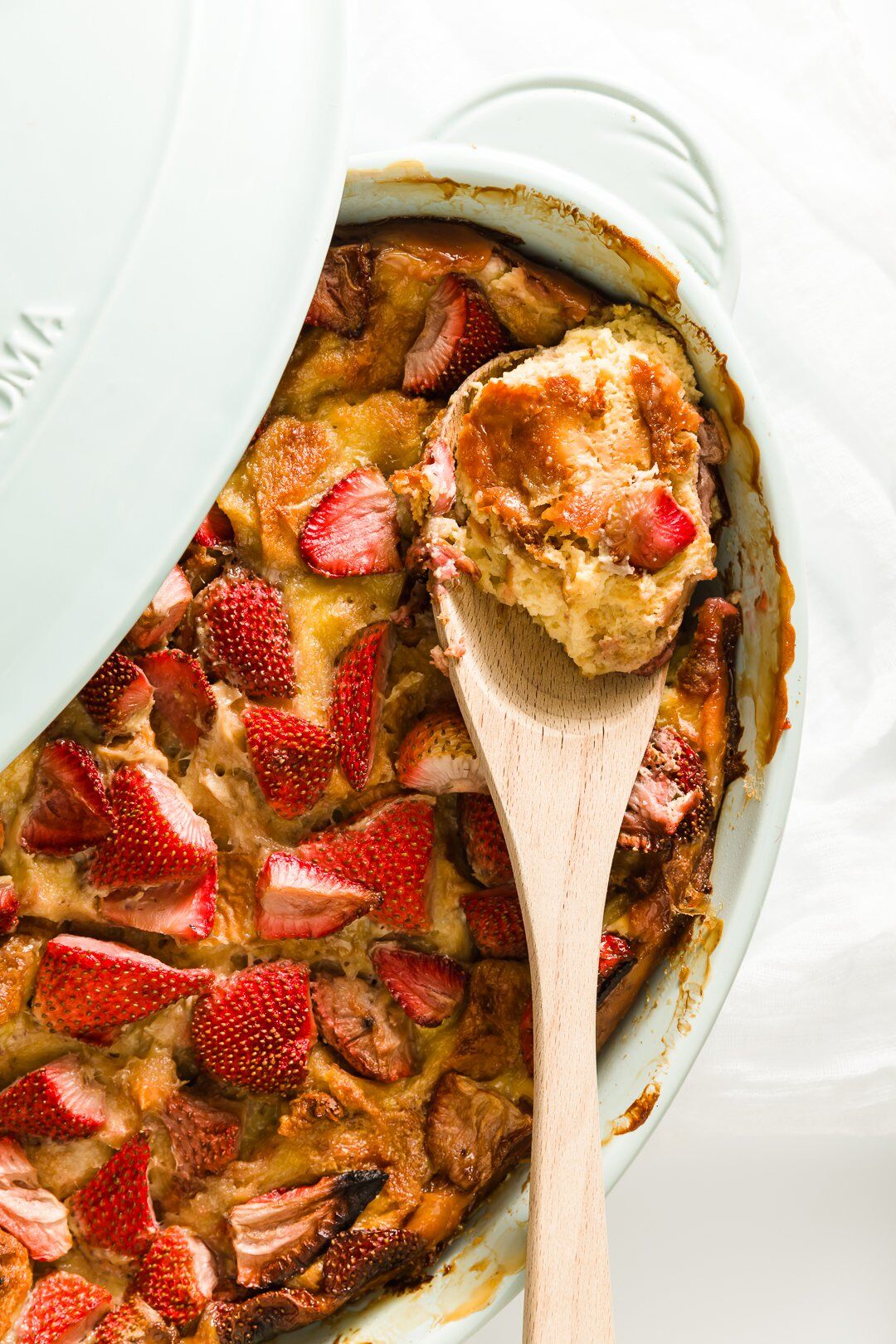 brioche French toast in a casserole dish with some scooped onto a serving spoon