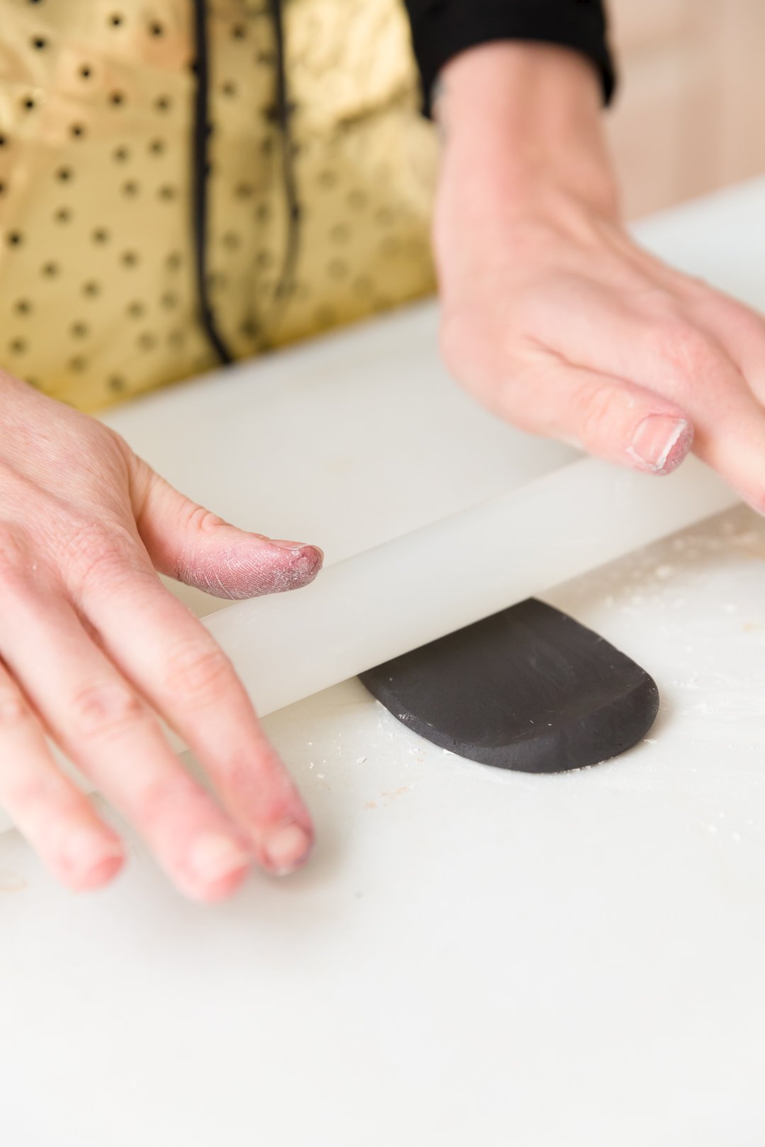 Rolling out black fondant with a fondant roller