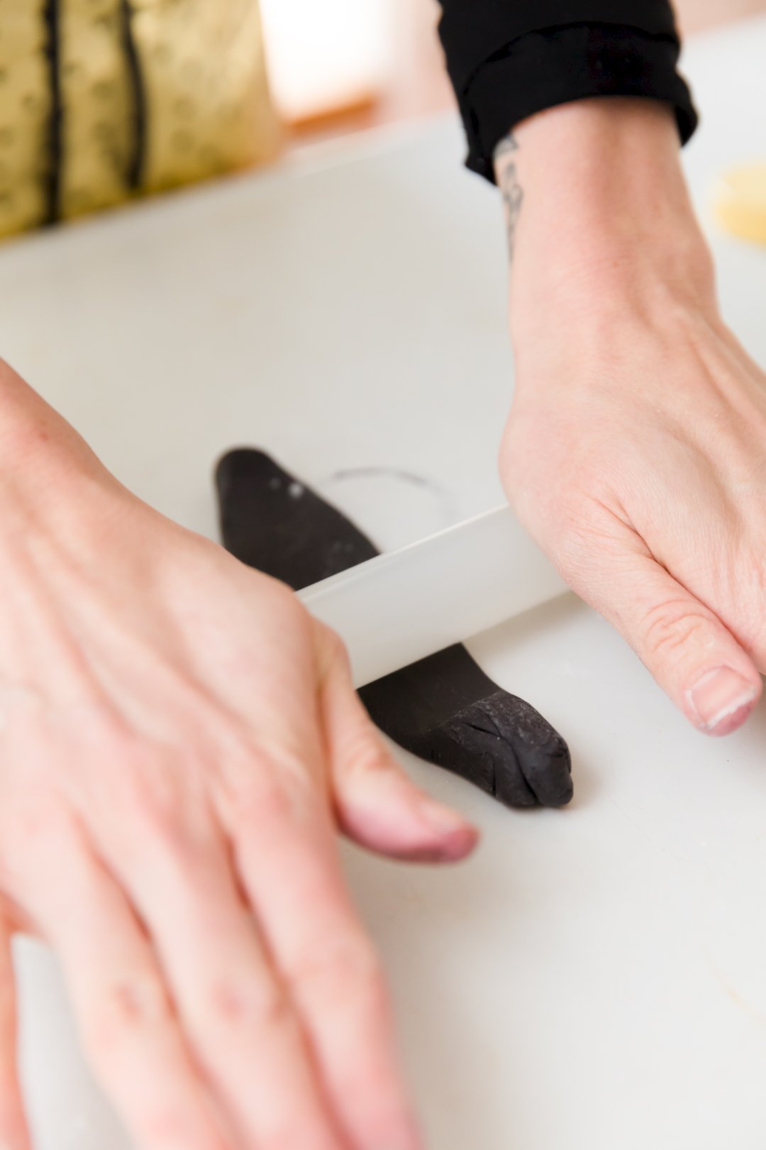 Using a fondant roller to roll a small piece of black fondant