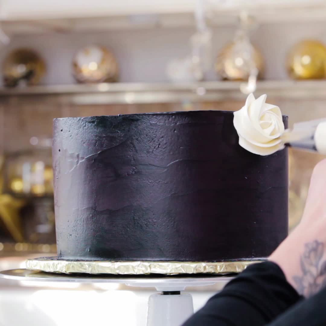 Piping a white rosette onto a black cake