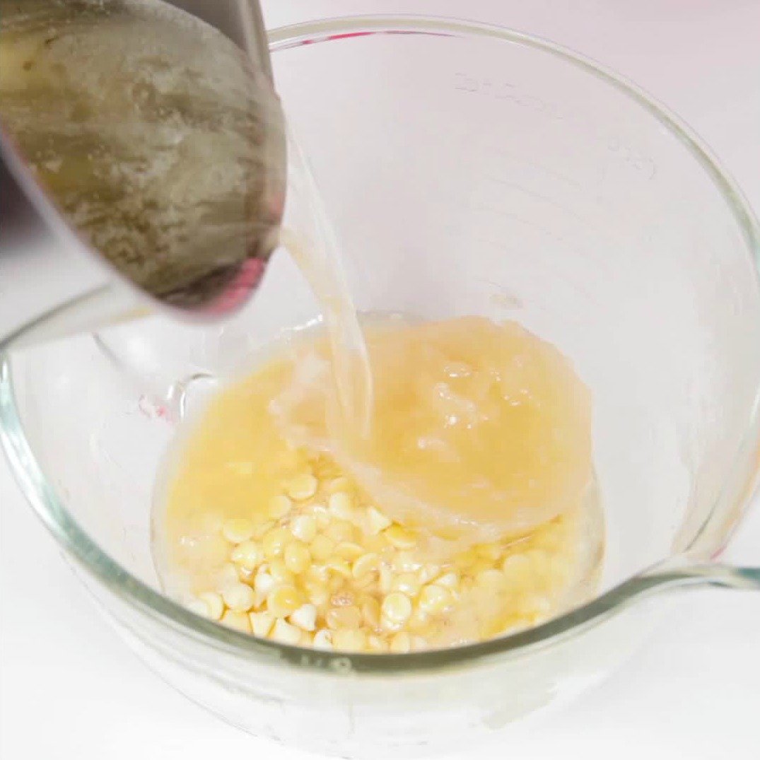 pouring sugar syrup over white chocolate and gelatin