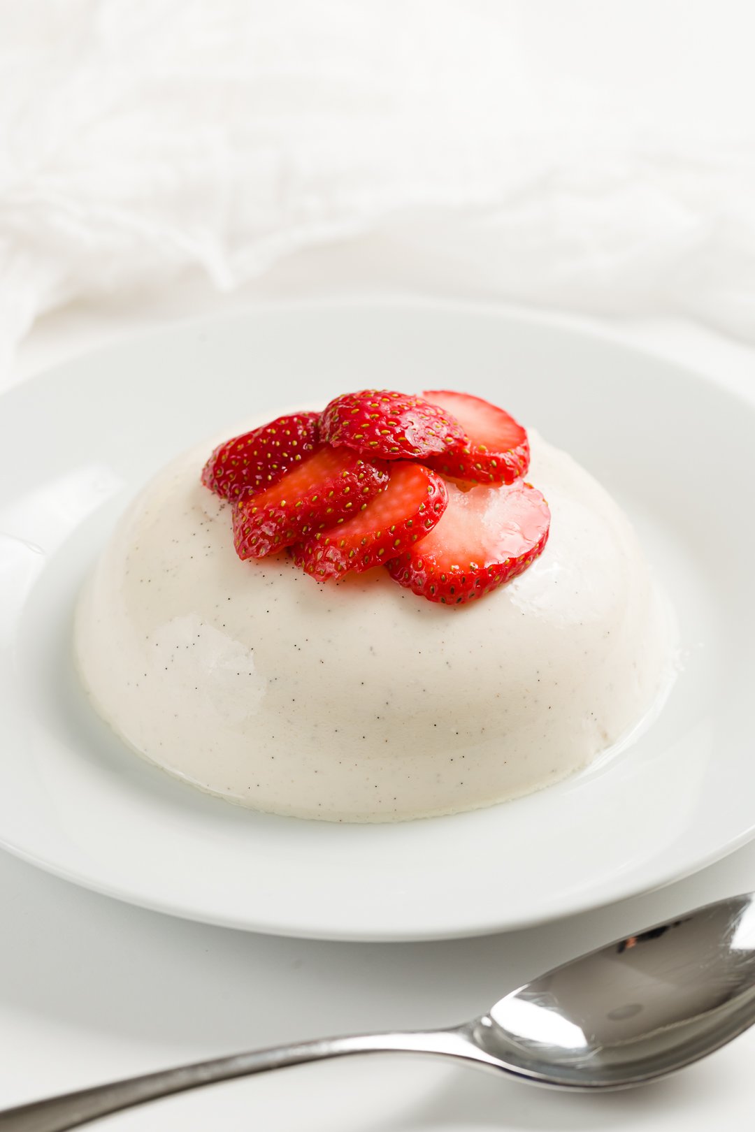 panna cotta on a plate served with macerated strawberries