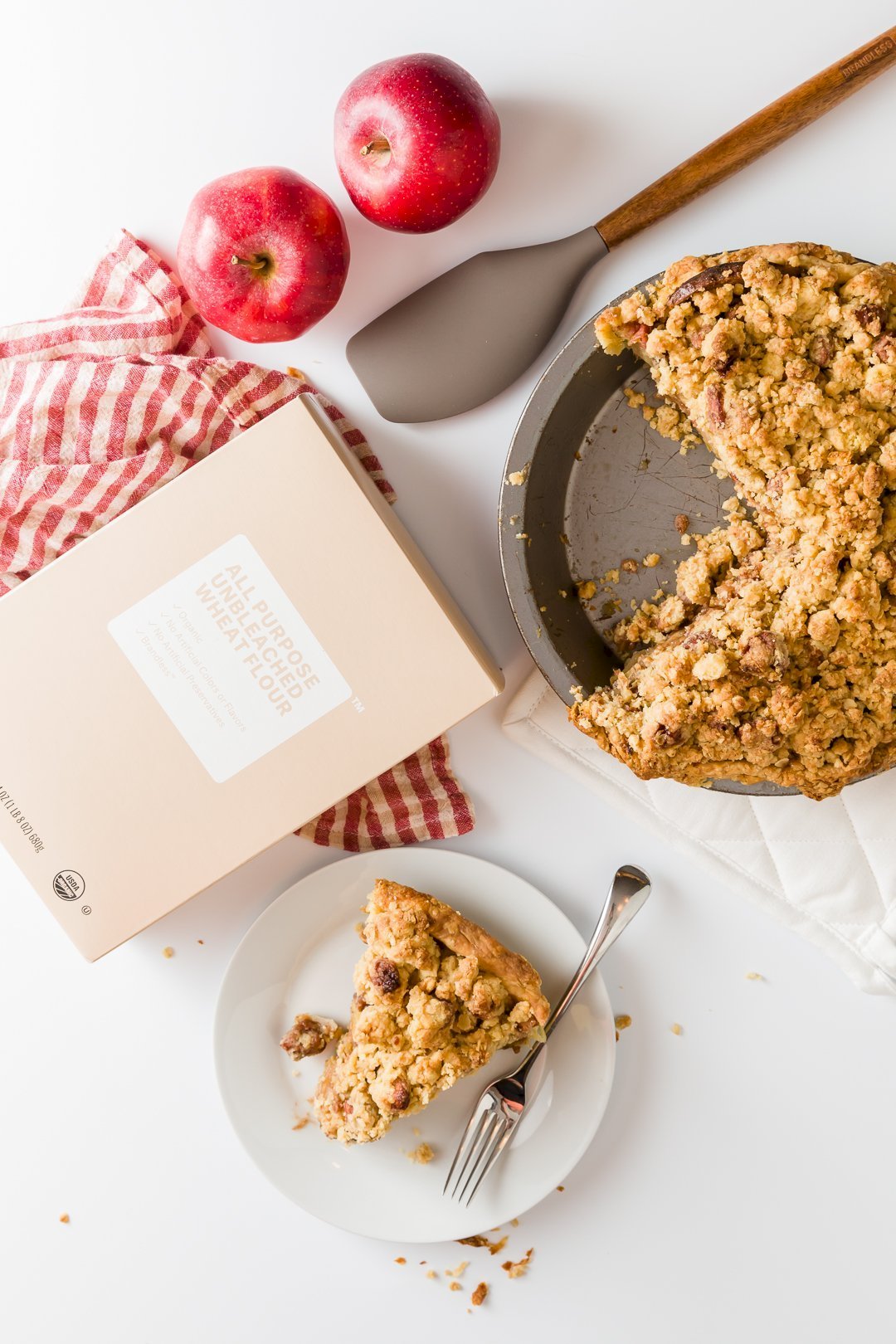 Dutch apple pie in pie plate and slice removed sitting on a plate