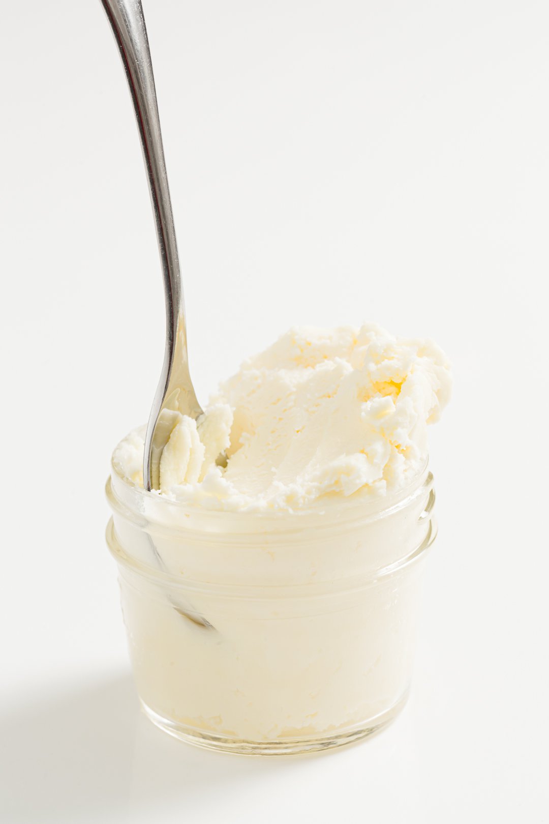 A jar of clotted cream with a spoon resting inside