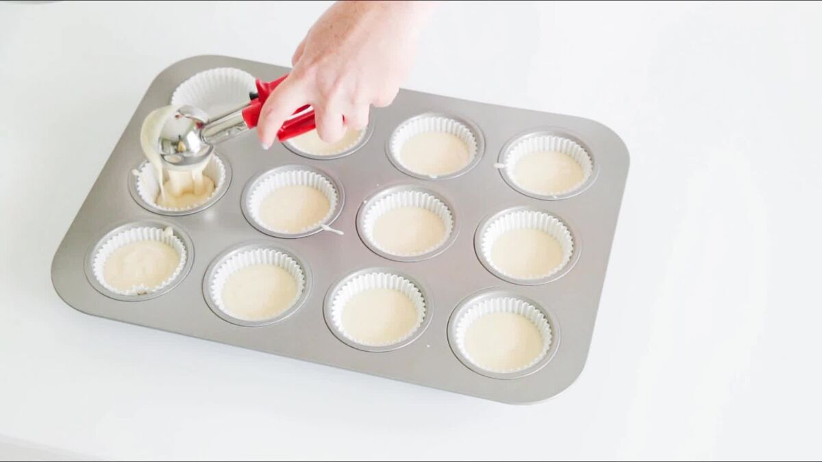 Using a scoop to fill cupcake liners with batter