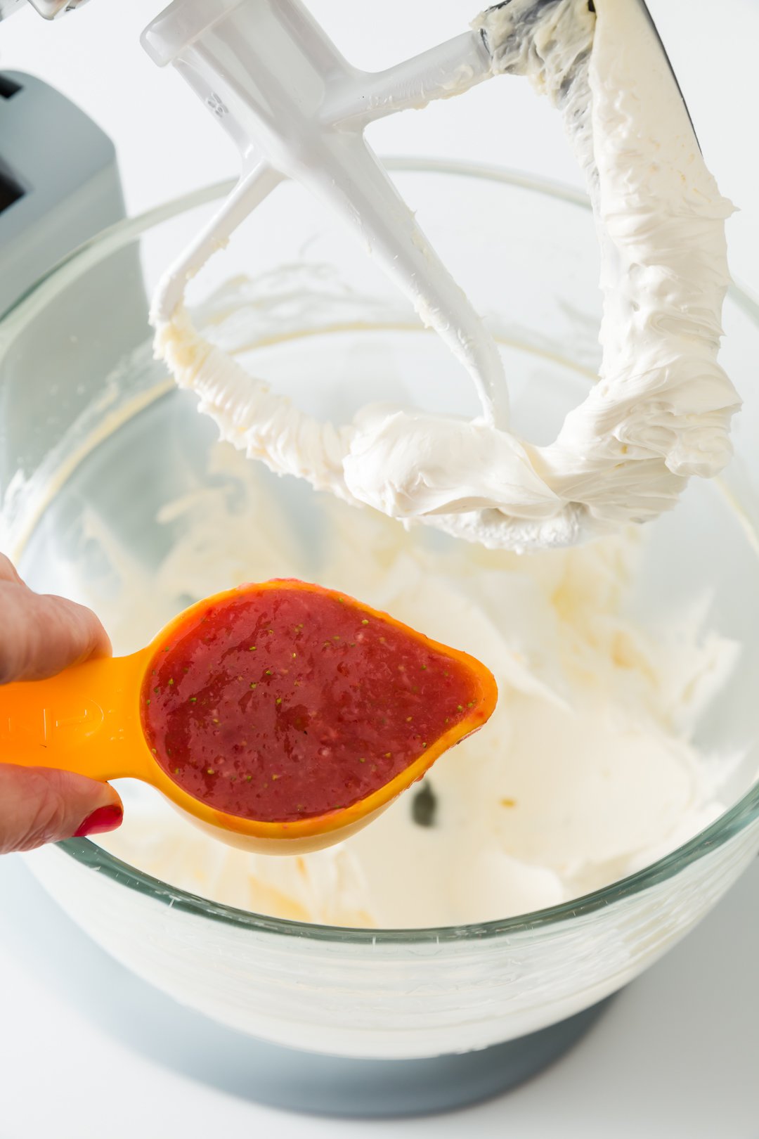 Adding strawberry puree to strawberry buttercream frosting