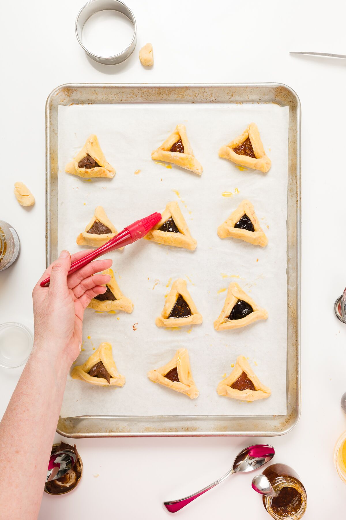 Brushing a trash of hamantaschen with egg
