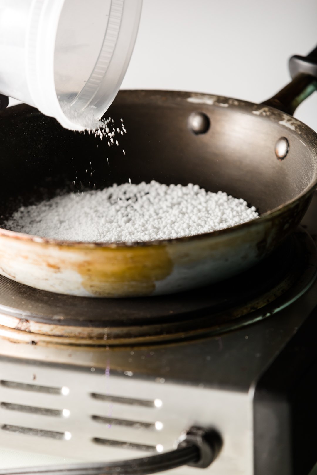 isomalt powder being poured into a skillet