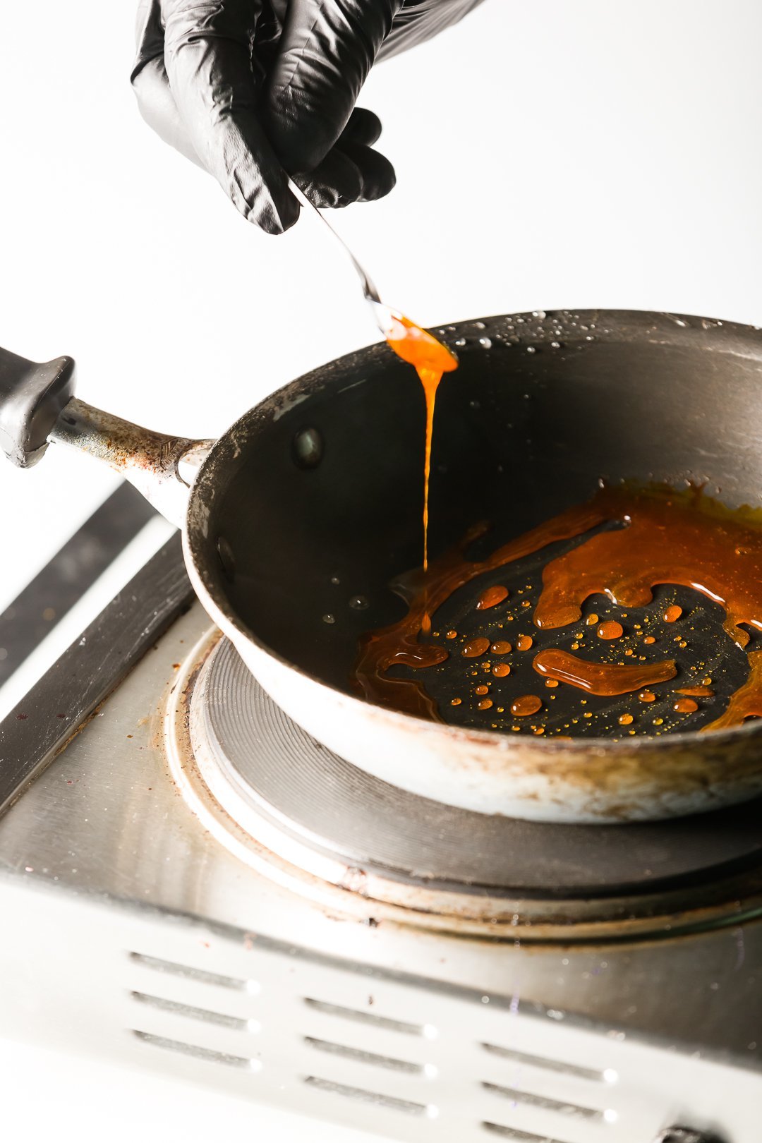 adding food coloring to a skillet of isomalt