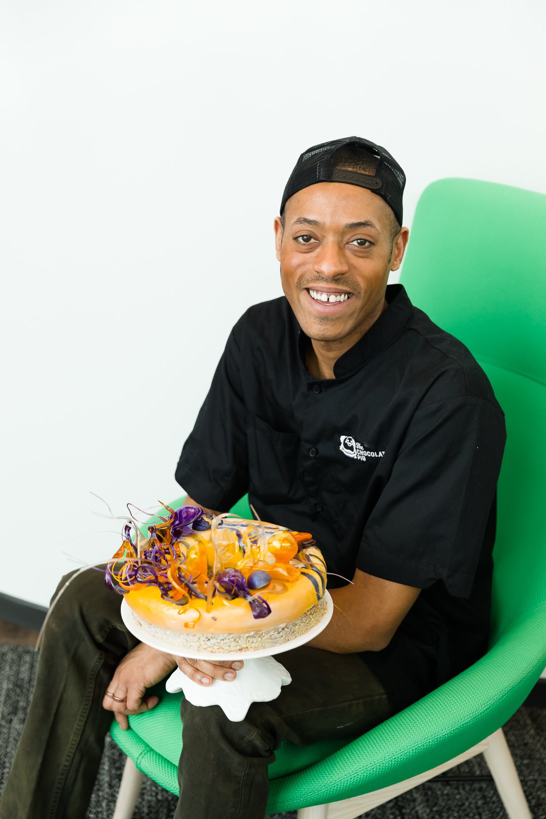 Tyler Davis on a green chair holding a cake