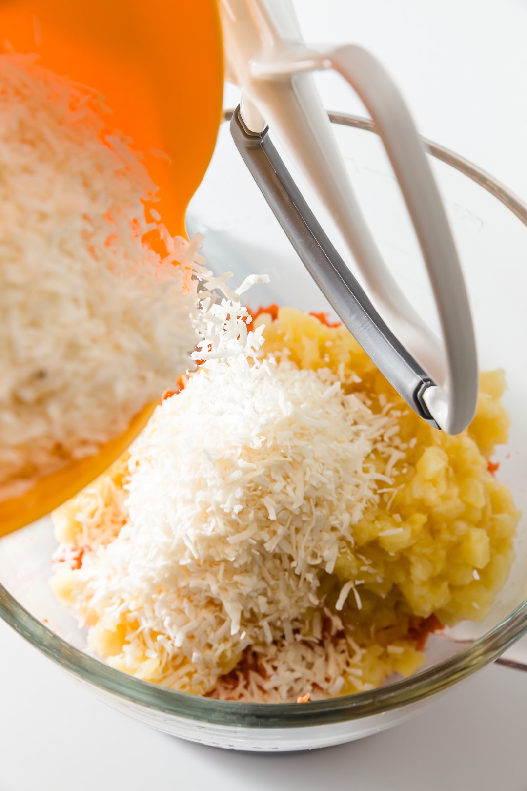 Shredded coconut being added to carrot cake batter