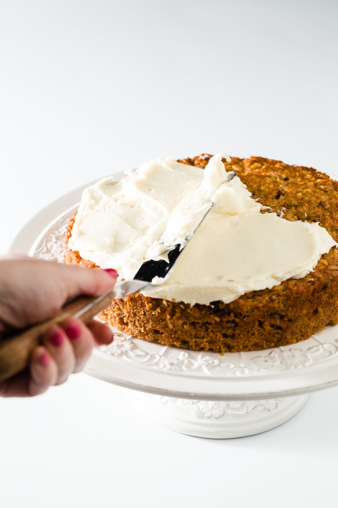 Spreading cream cheese frosting on a carrot cake