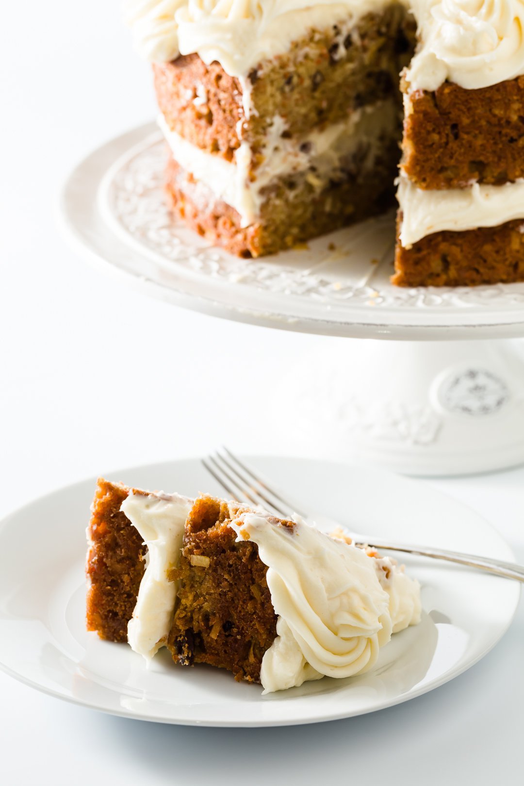 Slice of carrot cake in front of the whole cake