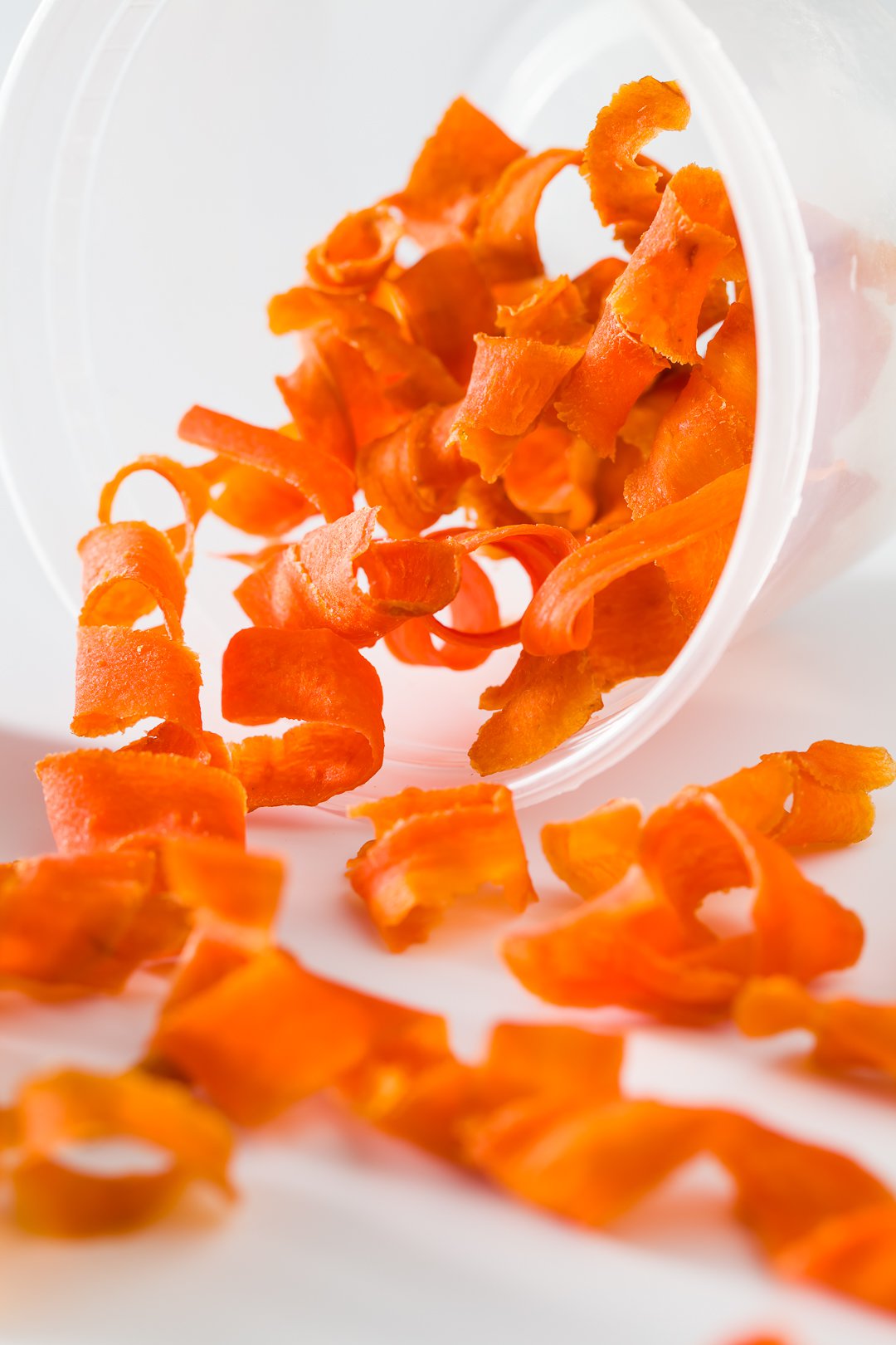 Candied carrot curls pouring out of a container