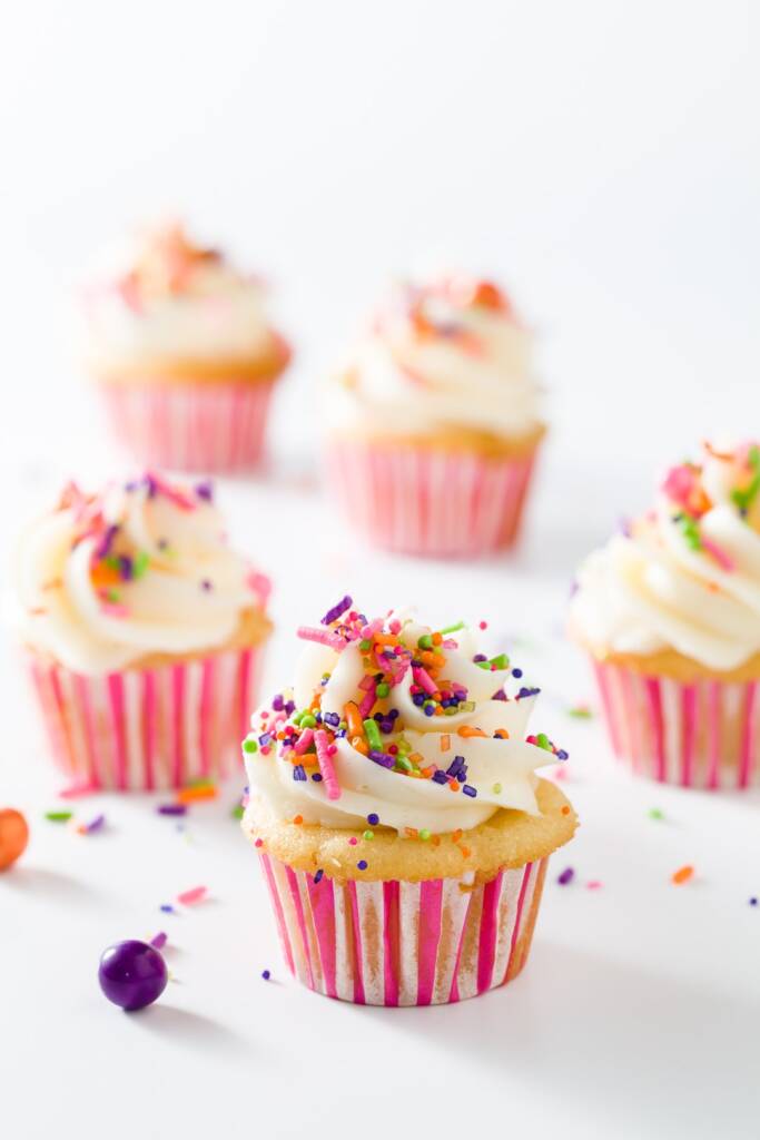 vijf mini vanille cupcakes met vanille botercrème in roze en witte voeringen