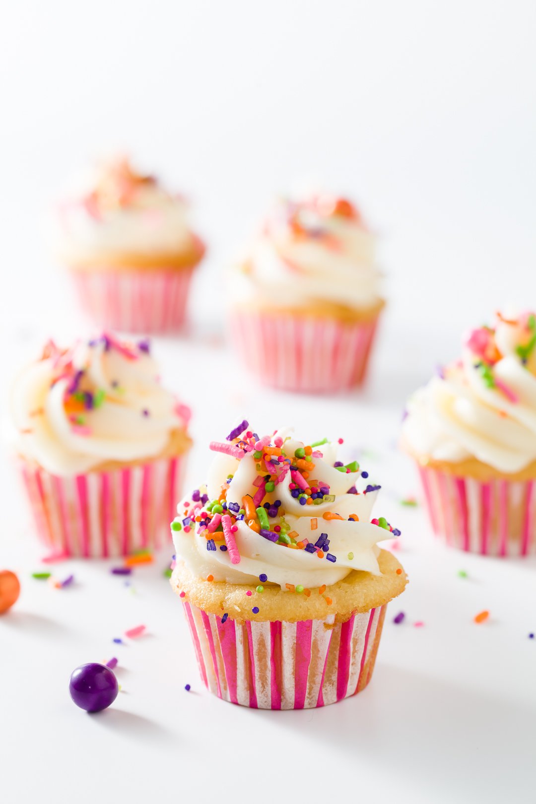 five mini vanilla cupcakes with vanilla buttercream in pink and white liners