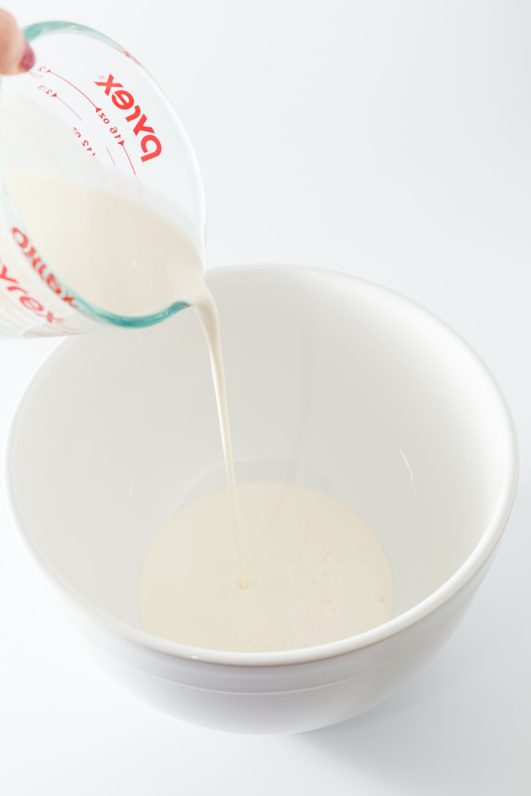 pouring heavy whipping cream into a mixing bowl