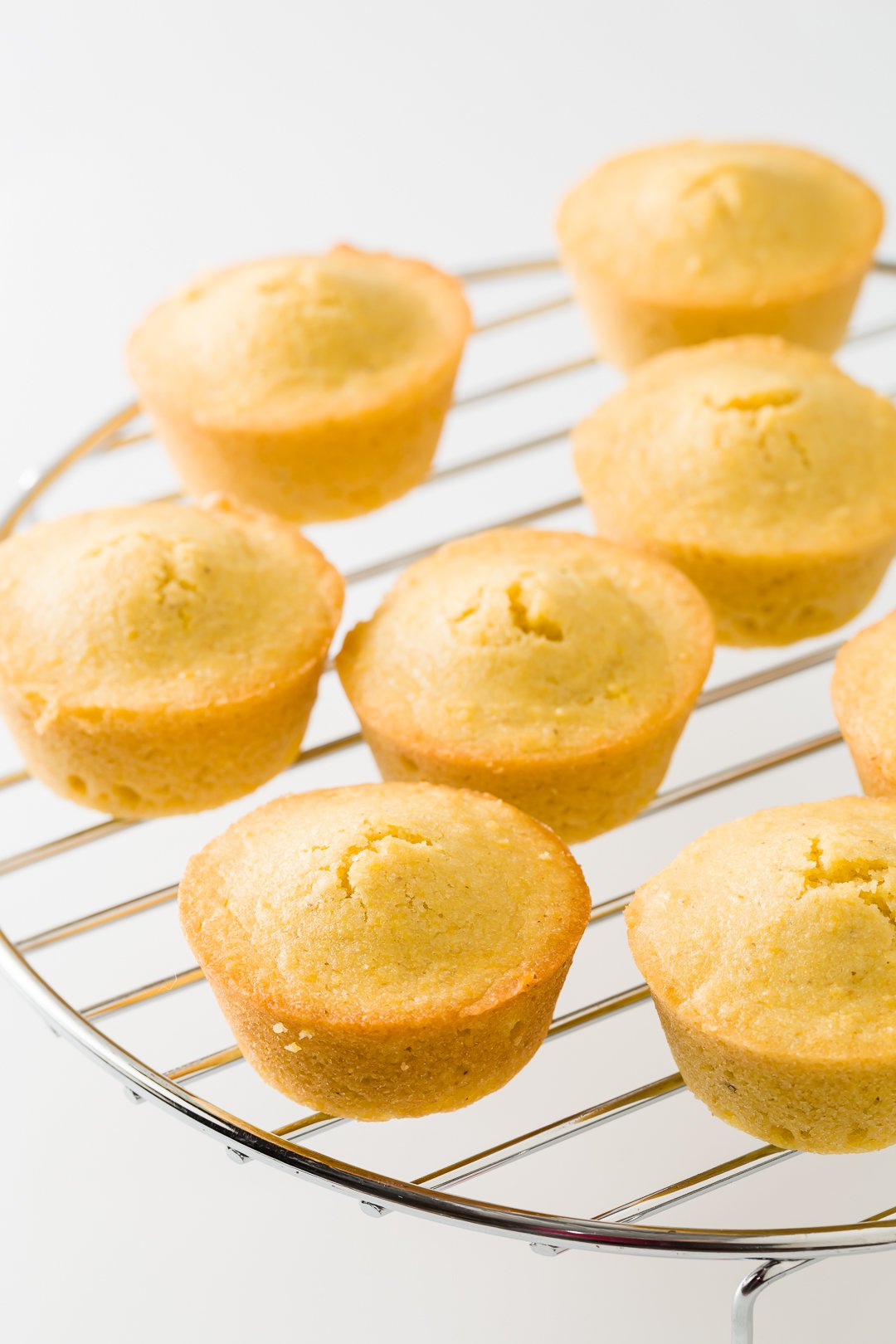 A number of cornbread muffins resting on a cooling rack