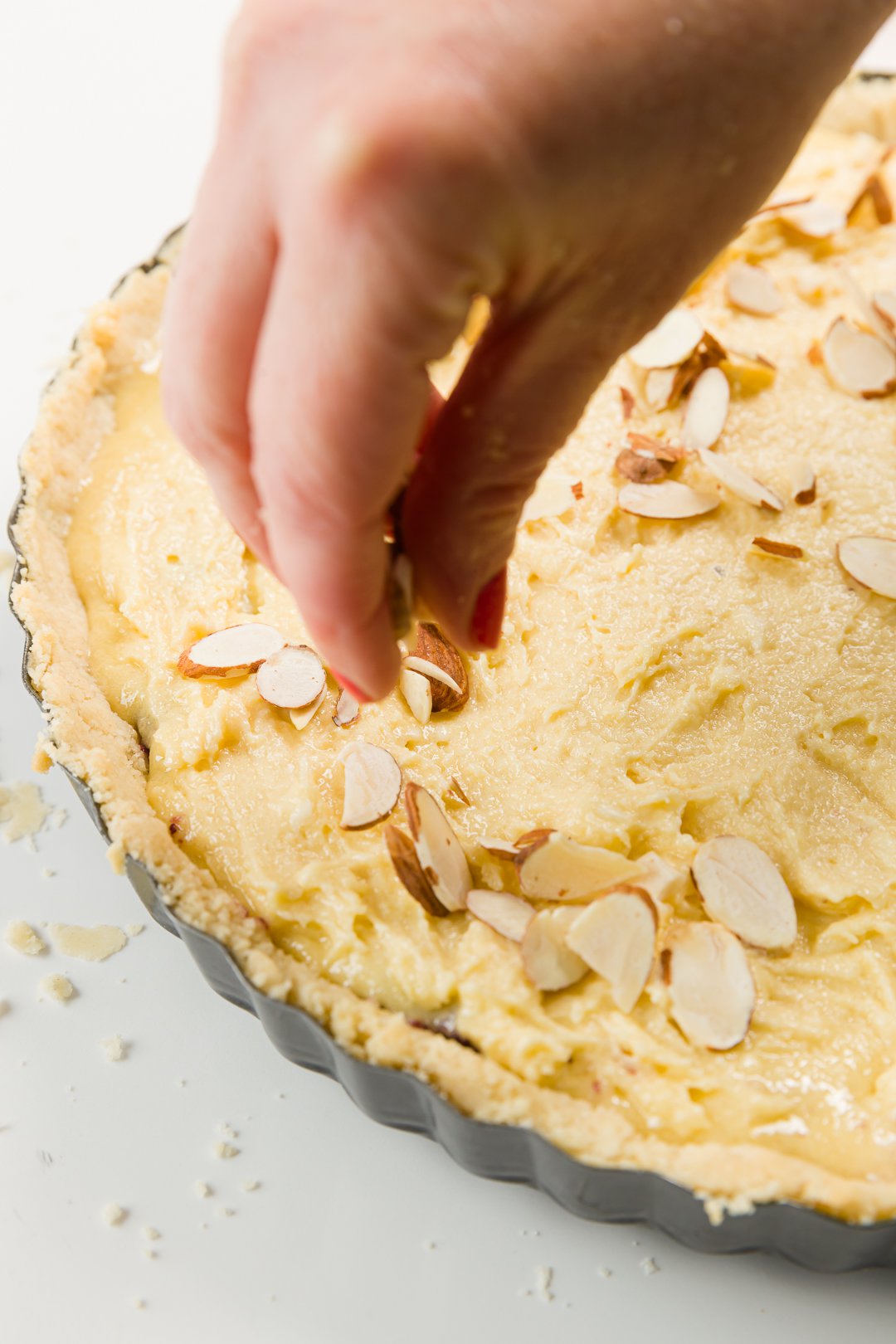 Sprinkling almond slivers on an unbaked tart