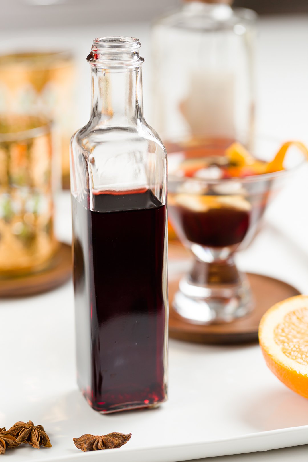 a jar of homemade grenadine surrounded by cocktail-making supplies