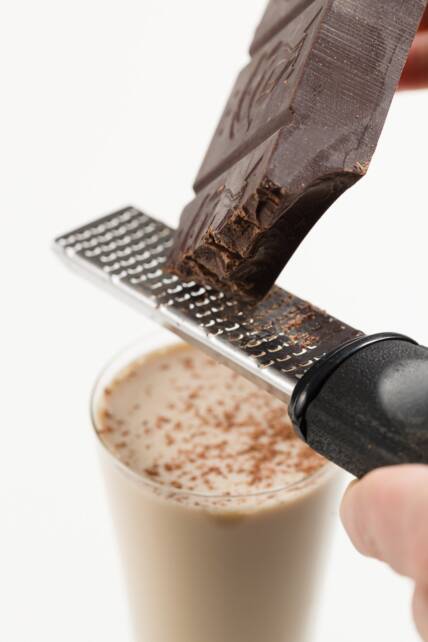 Afeitar chocolate encima de un cóctel de deslizamiento de lodo en un vaso