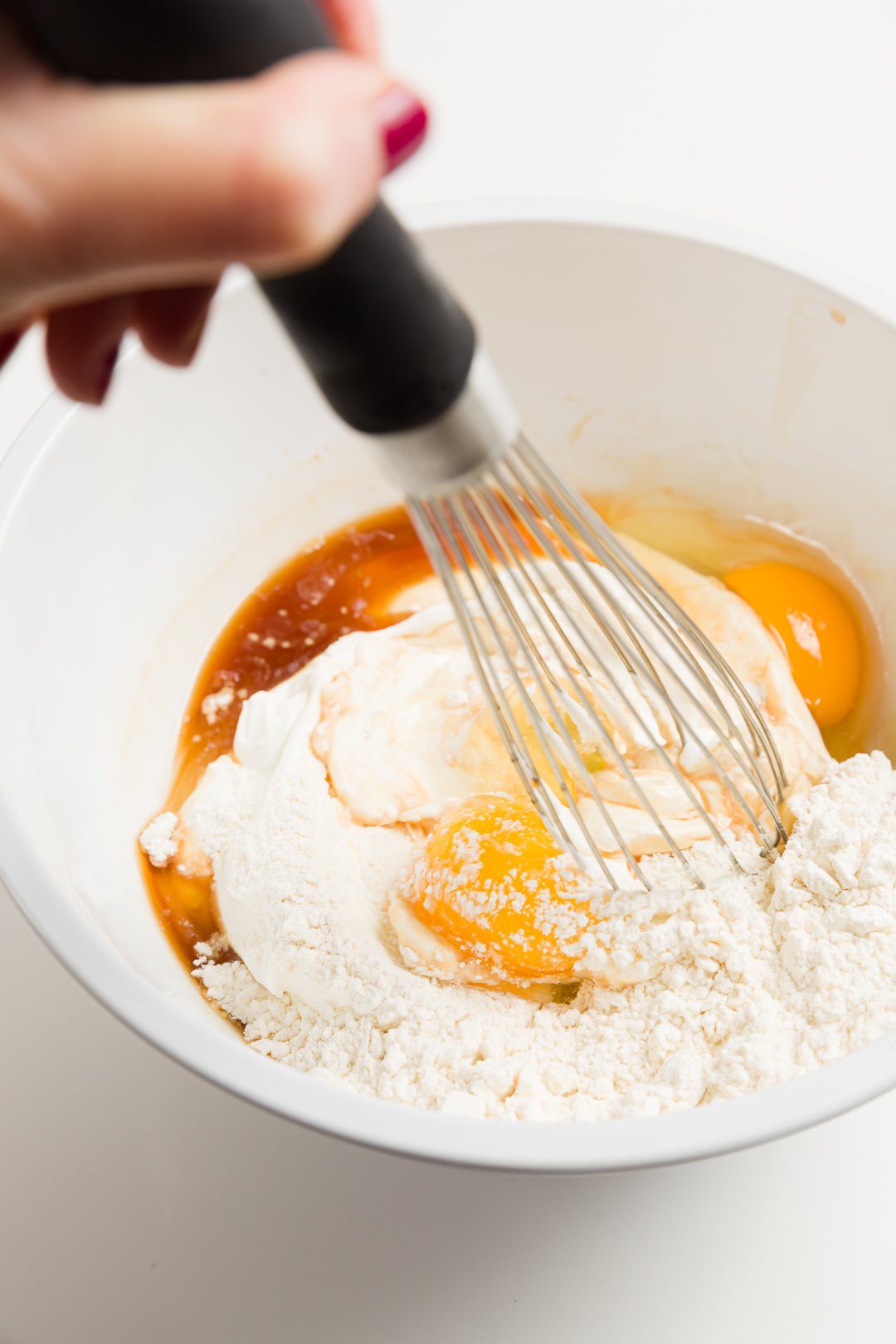 looking into a bowl where Stef whisks eggs, sour cream, vanilla, and flour until fully combined