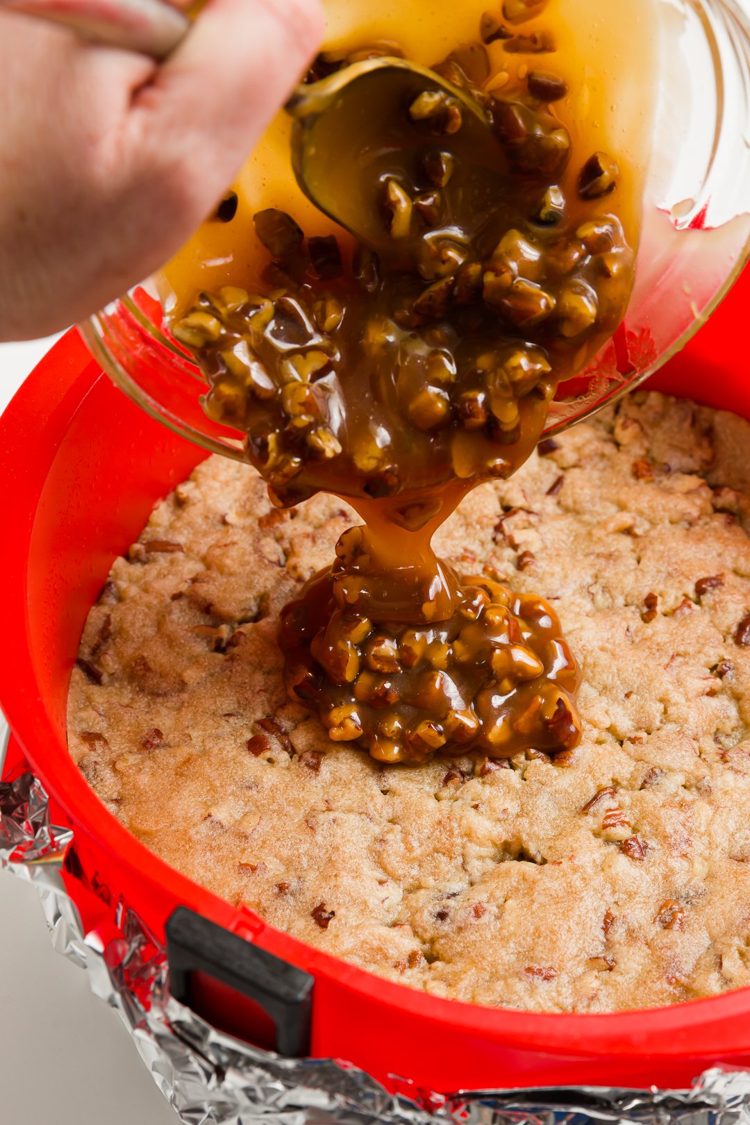 Pouring caramel and pecans over crust