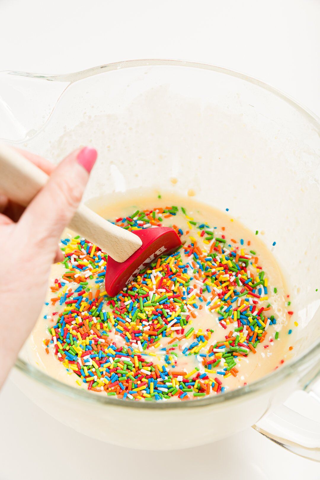 Stirring sprinkles into funfetti cupcake batter