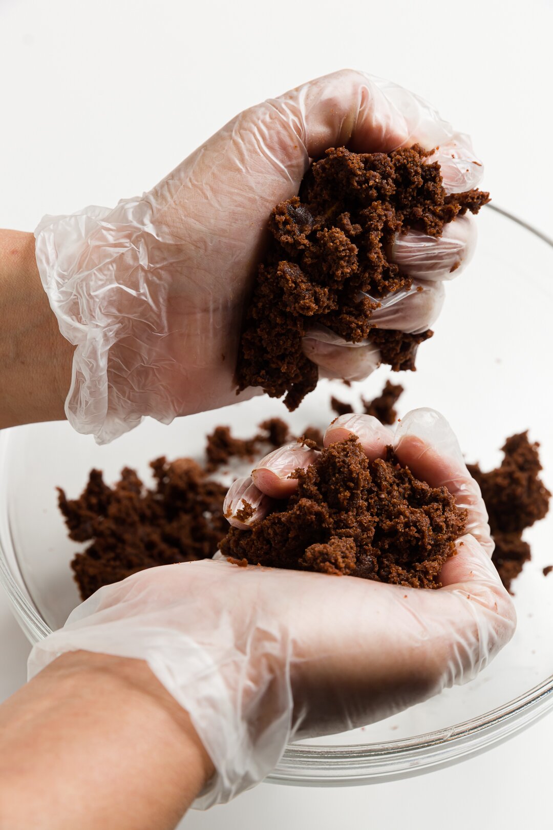 gloved hands smooshing leftover cake