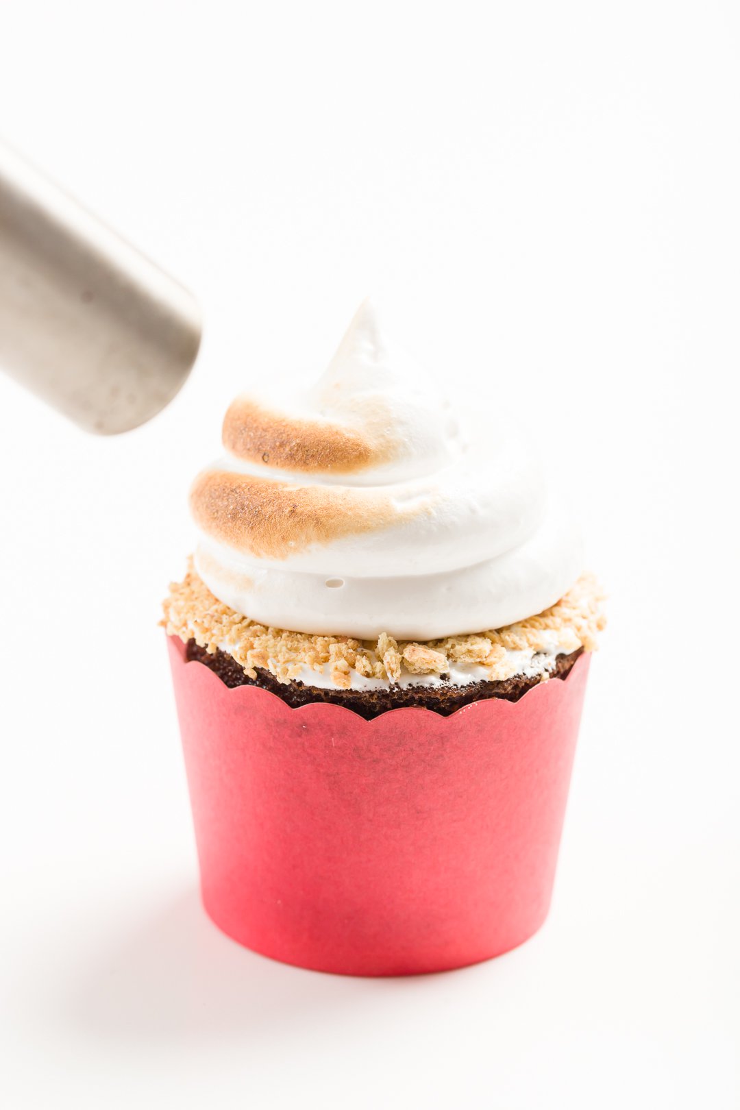 head-on view of using a culinary torch to toast marshmallow frosting