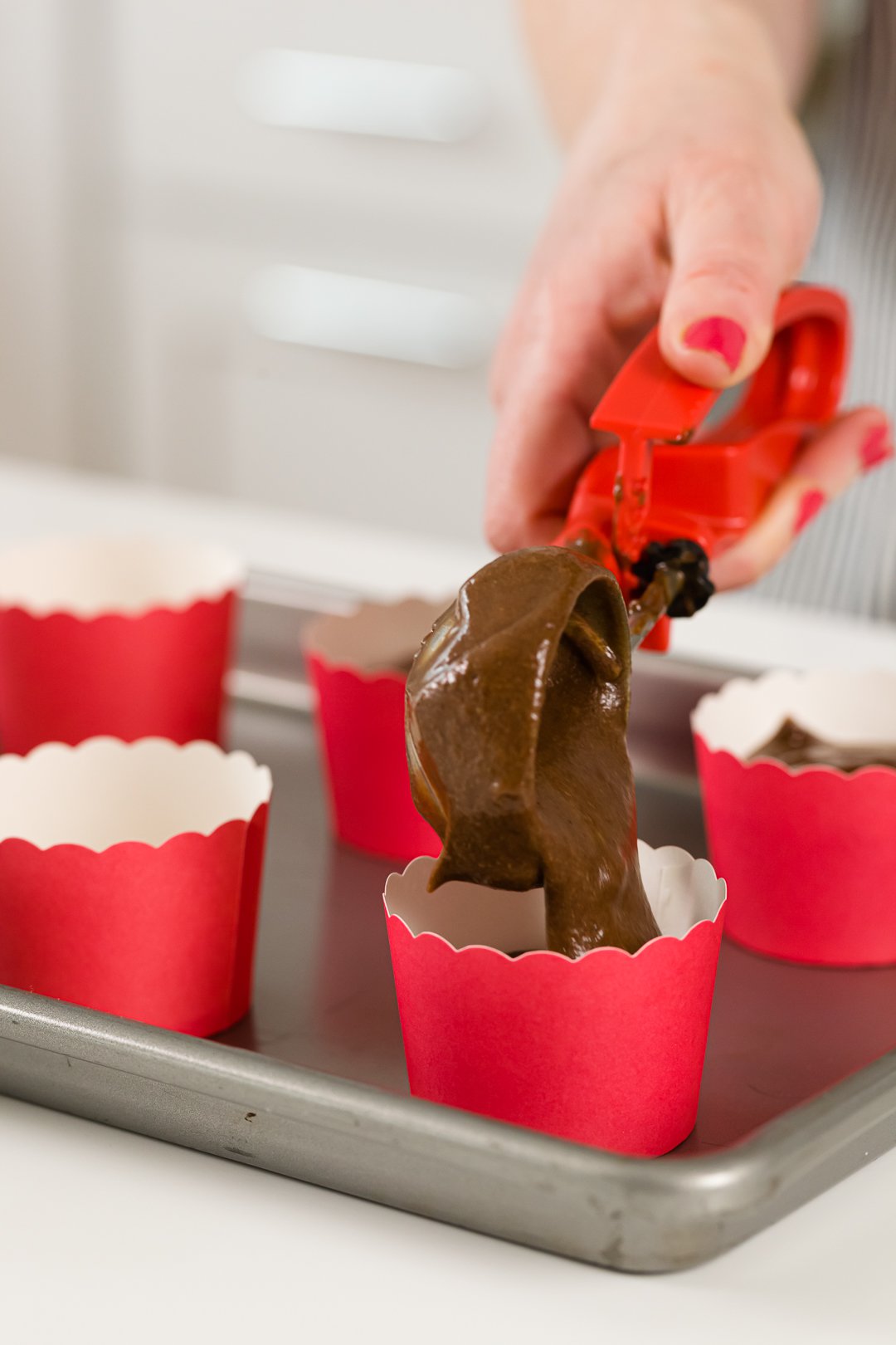 filling baking cups with chocolate cupcake batter