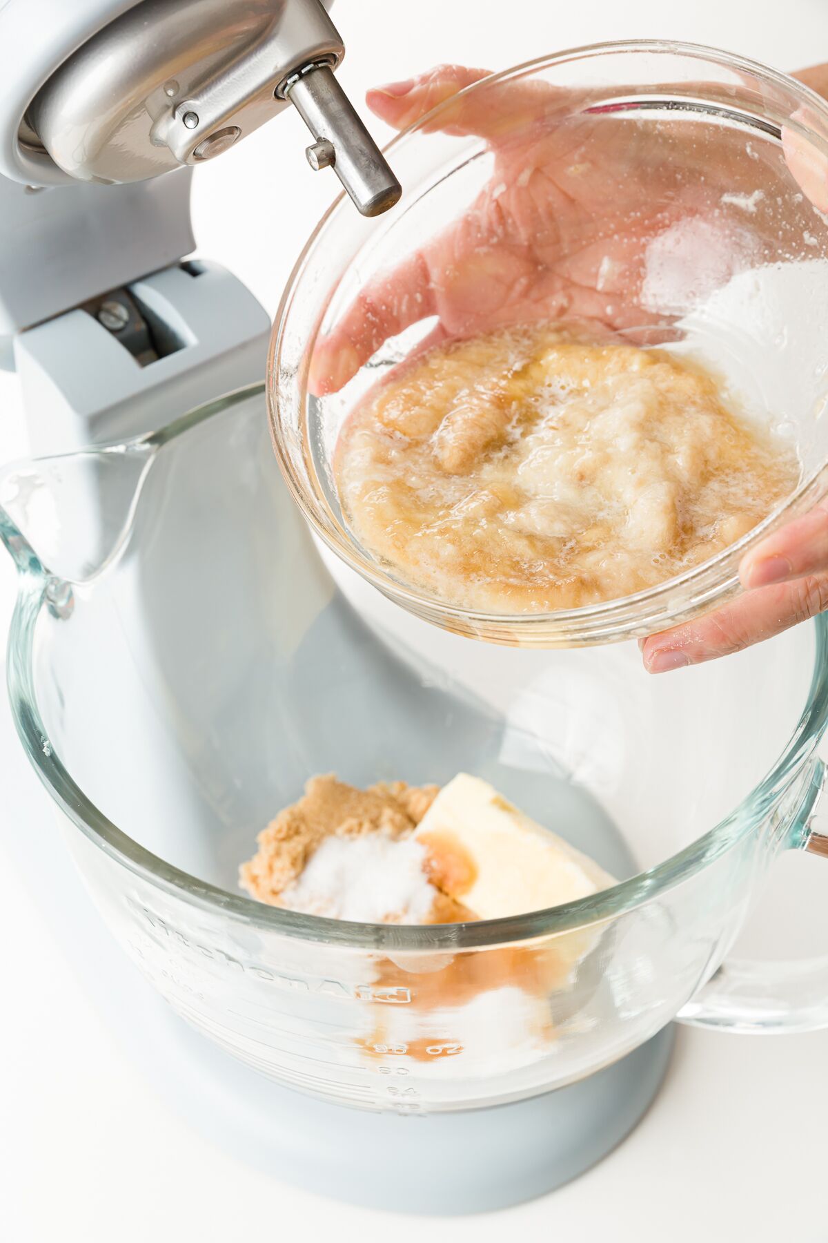 Pouring a bowl of mashed bananas into a stand mixer