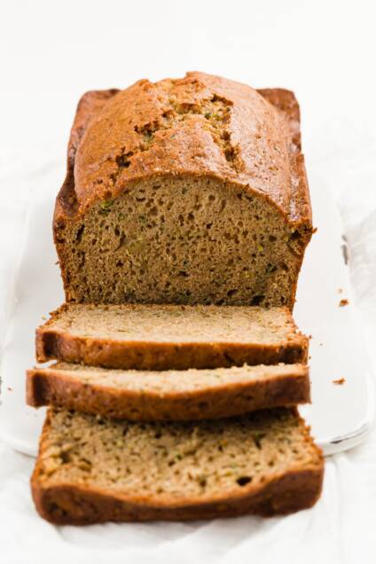 A loaf of zucchini bread with slices falling off the front of it