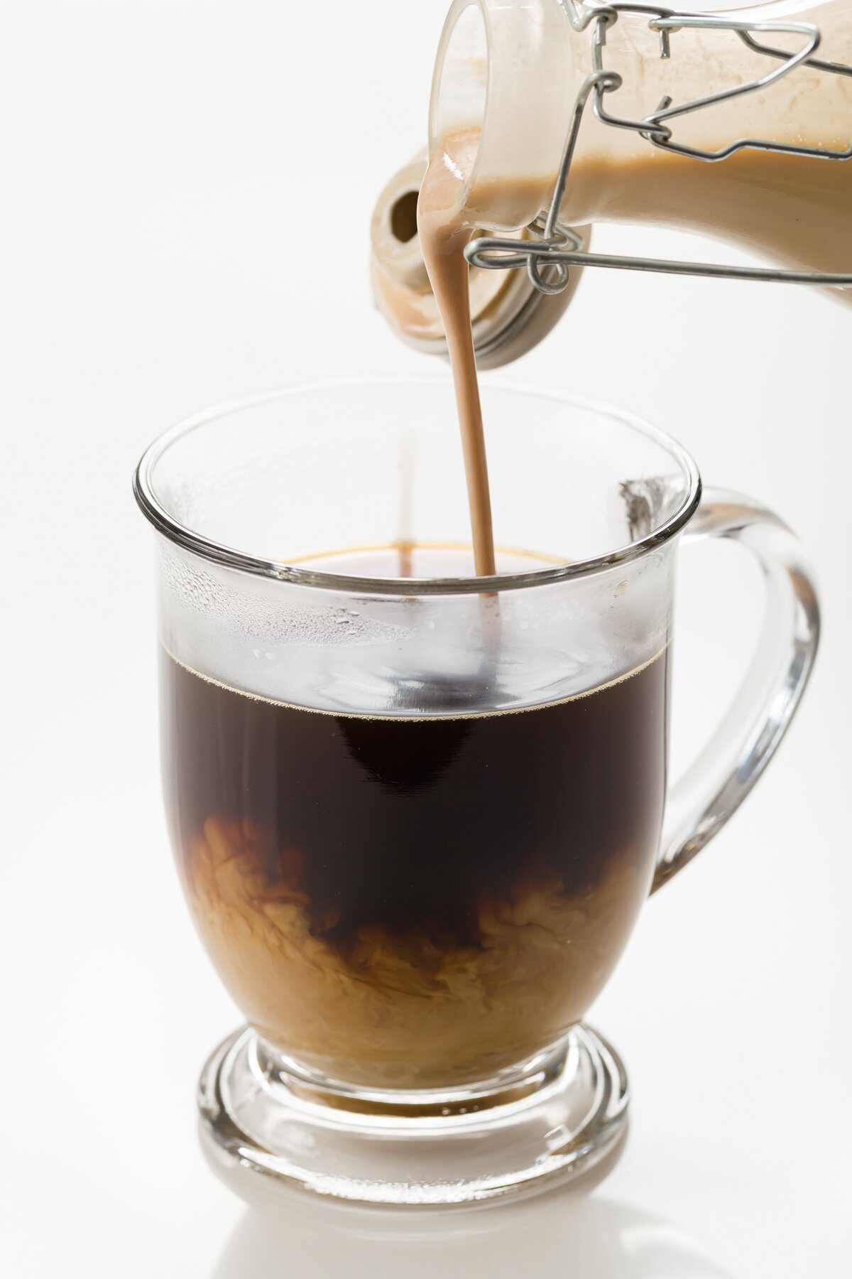 tight shot of homemade Baileys being poured into hot coffee