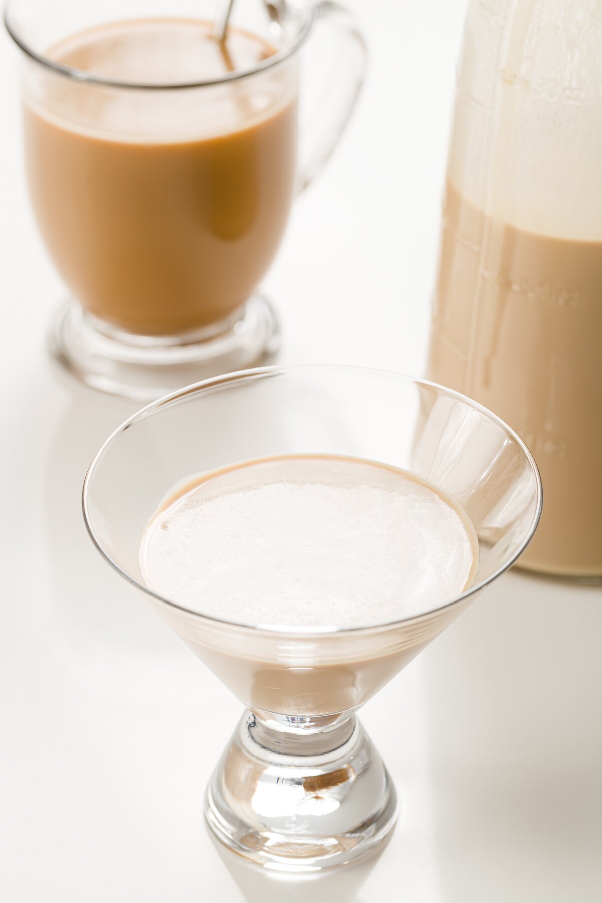 tight shot of a glass with homemade Baileys and a bottle and coffee cocktail in the background