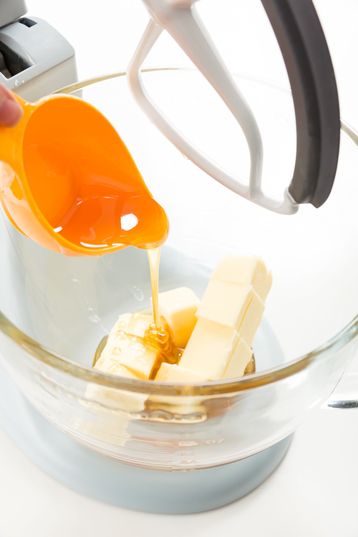 Pour honey onto butter in the glass bowl of a stand mixer.
