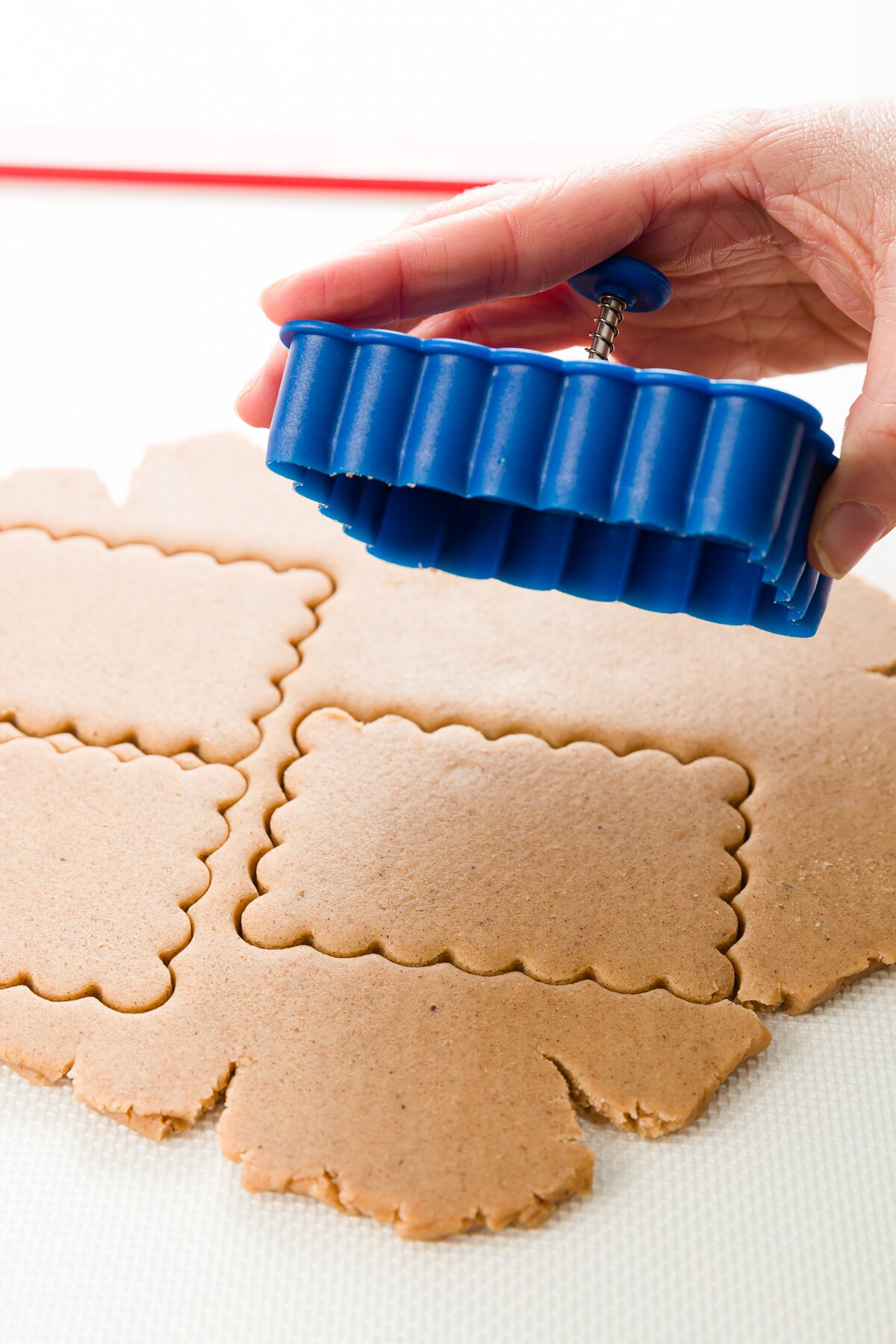 a sheet of cookie dough just cut with a scalloped rectangular cookie cutter