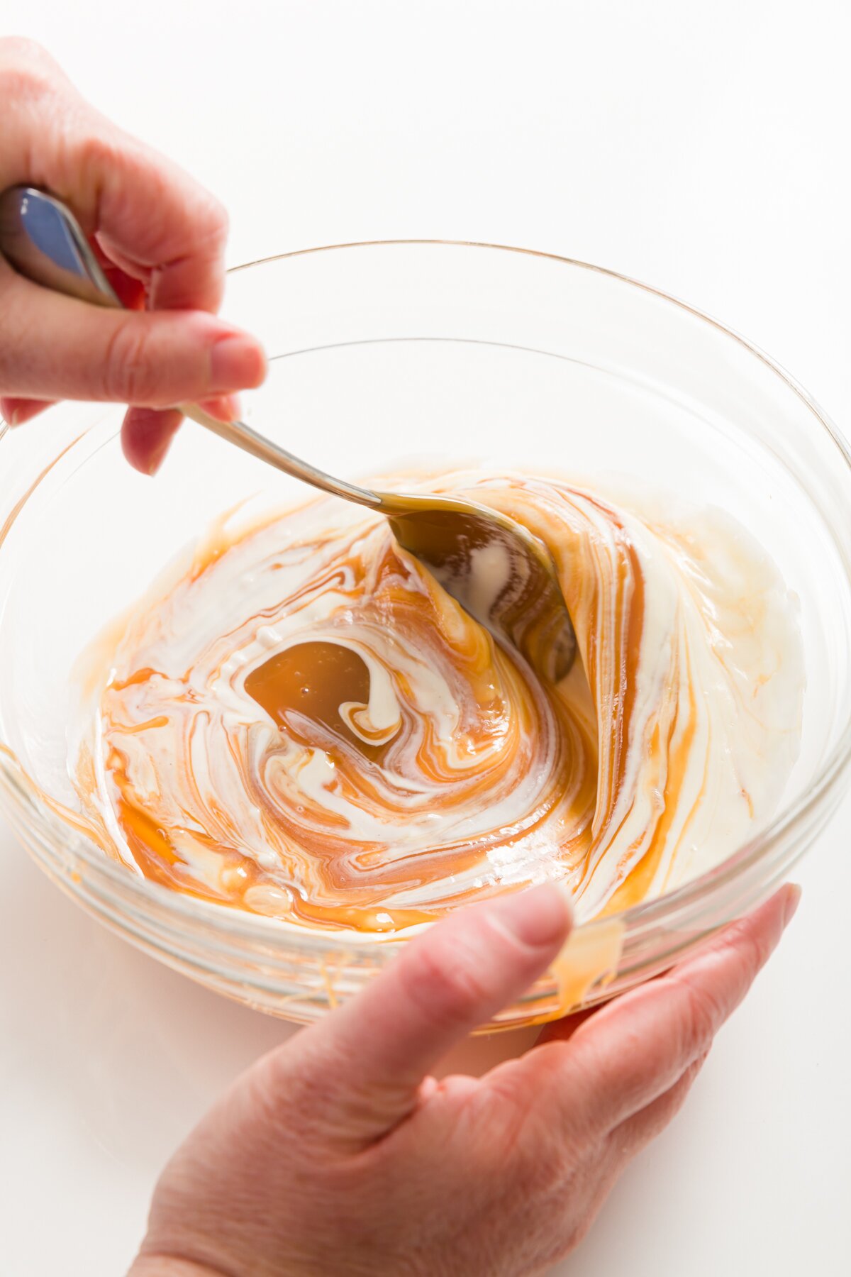 Mixing dulce de leche into cheesecake batter in a small glass bowl