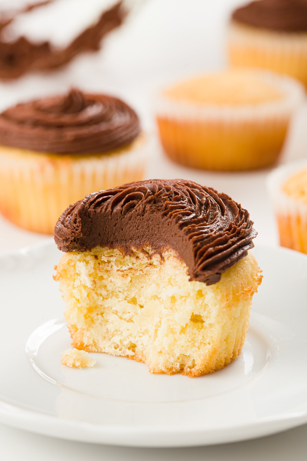 tight shot of an interior of a pound cake cupcake frosted with chocolate ganache frosting with other cupcakes in the background