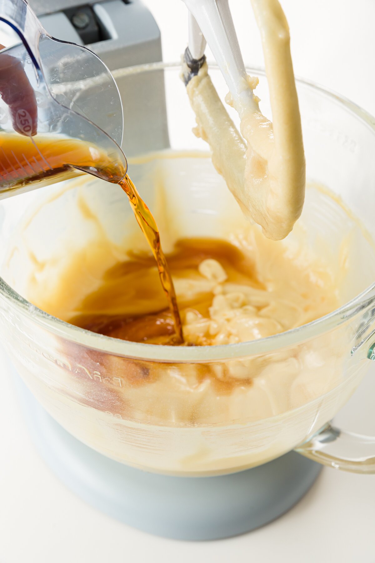 rum being poured into batter in a stand mixer