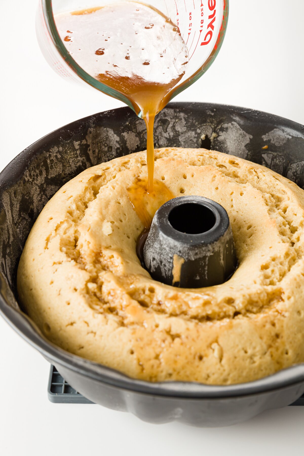 medium shot of Stef pouring rum syrup into the cake still in the Bundt pan