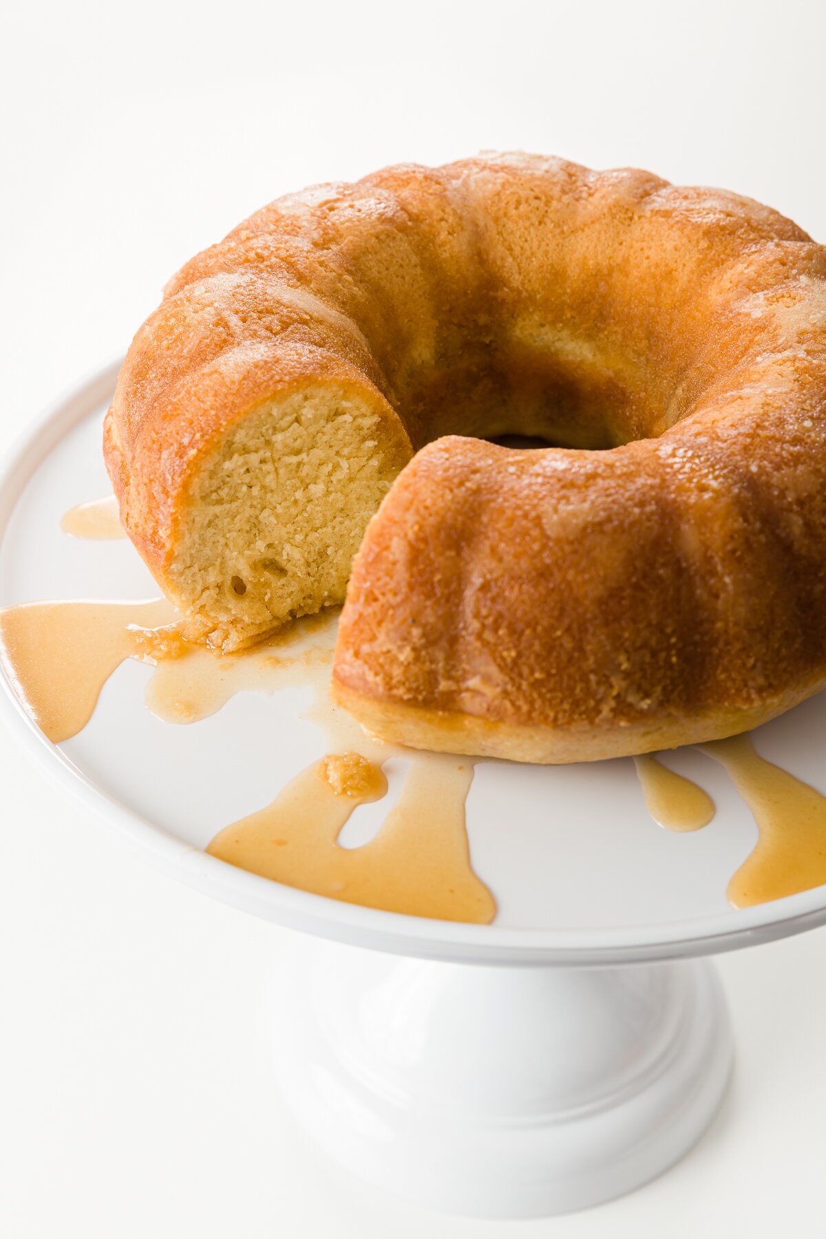 medium shot of a rum cake with a slice removed resting on a cake stand
