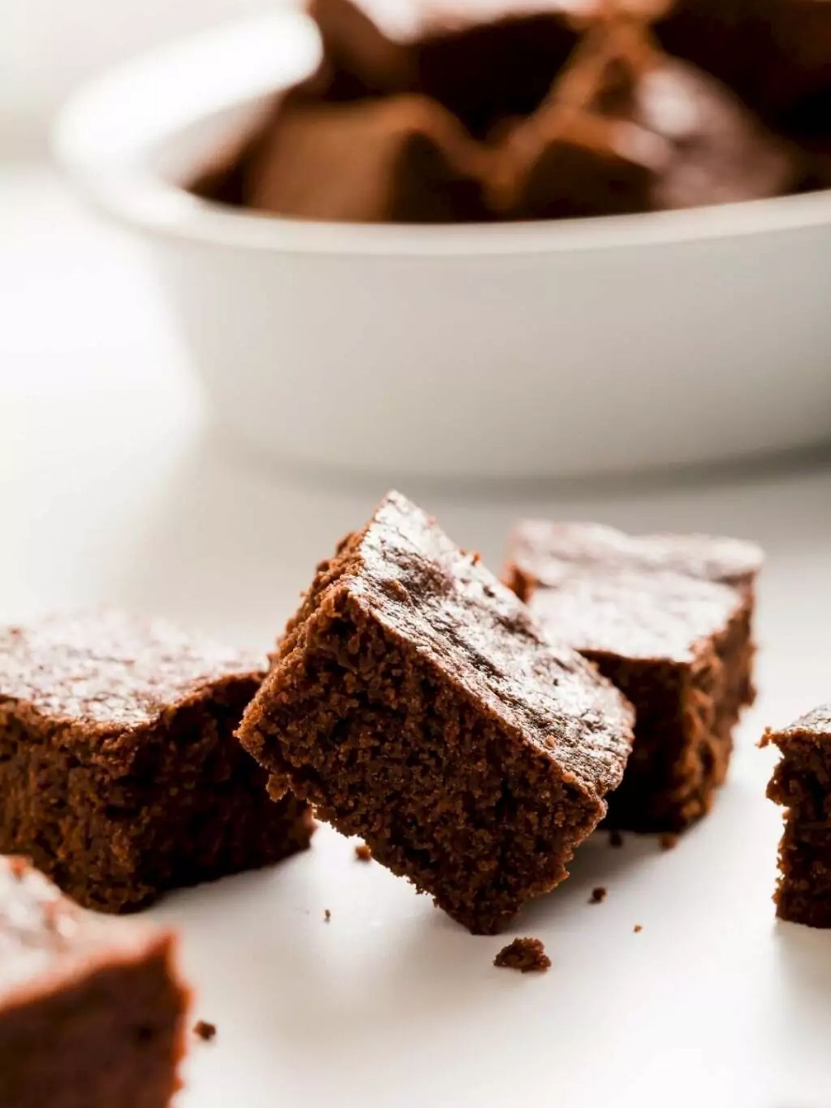 Cakey brownies toppled on top of each other on a white background.