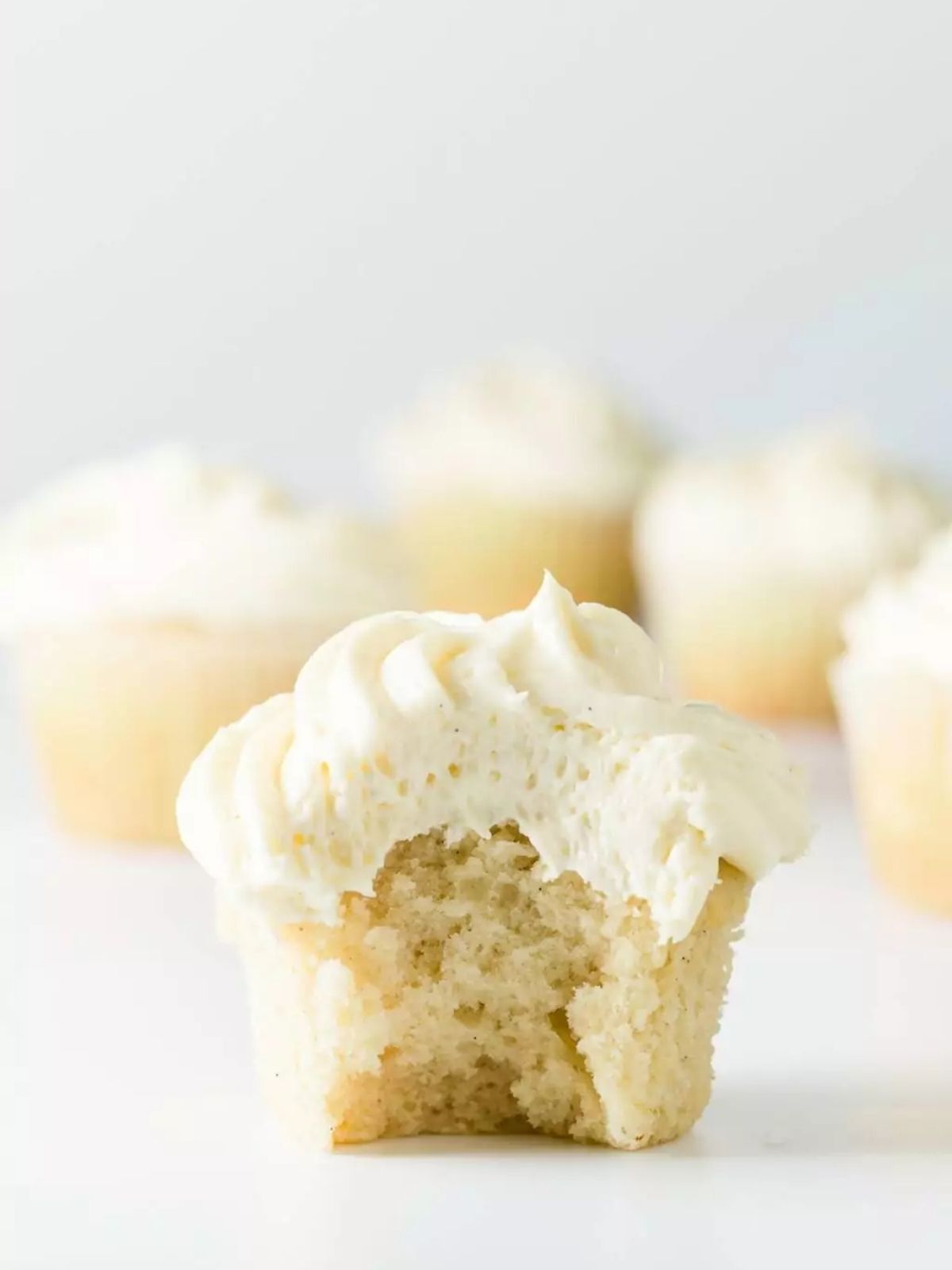 Vanilla cupcakes with a bite taken out.