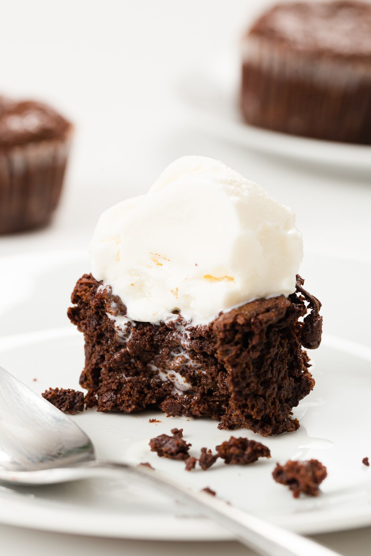 Flourless chocolate cupcake cut open on a plate with a dripping scoop of ice cream on top