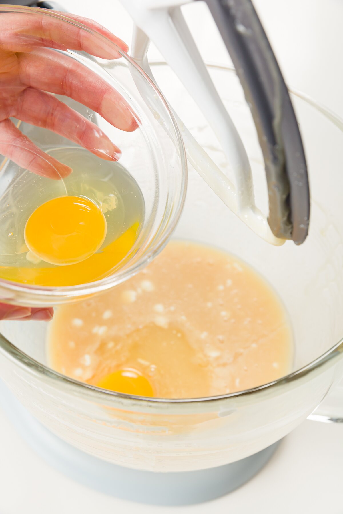 Adding egg to mixer bowl with batter
