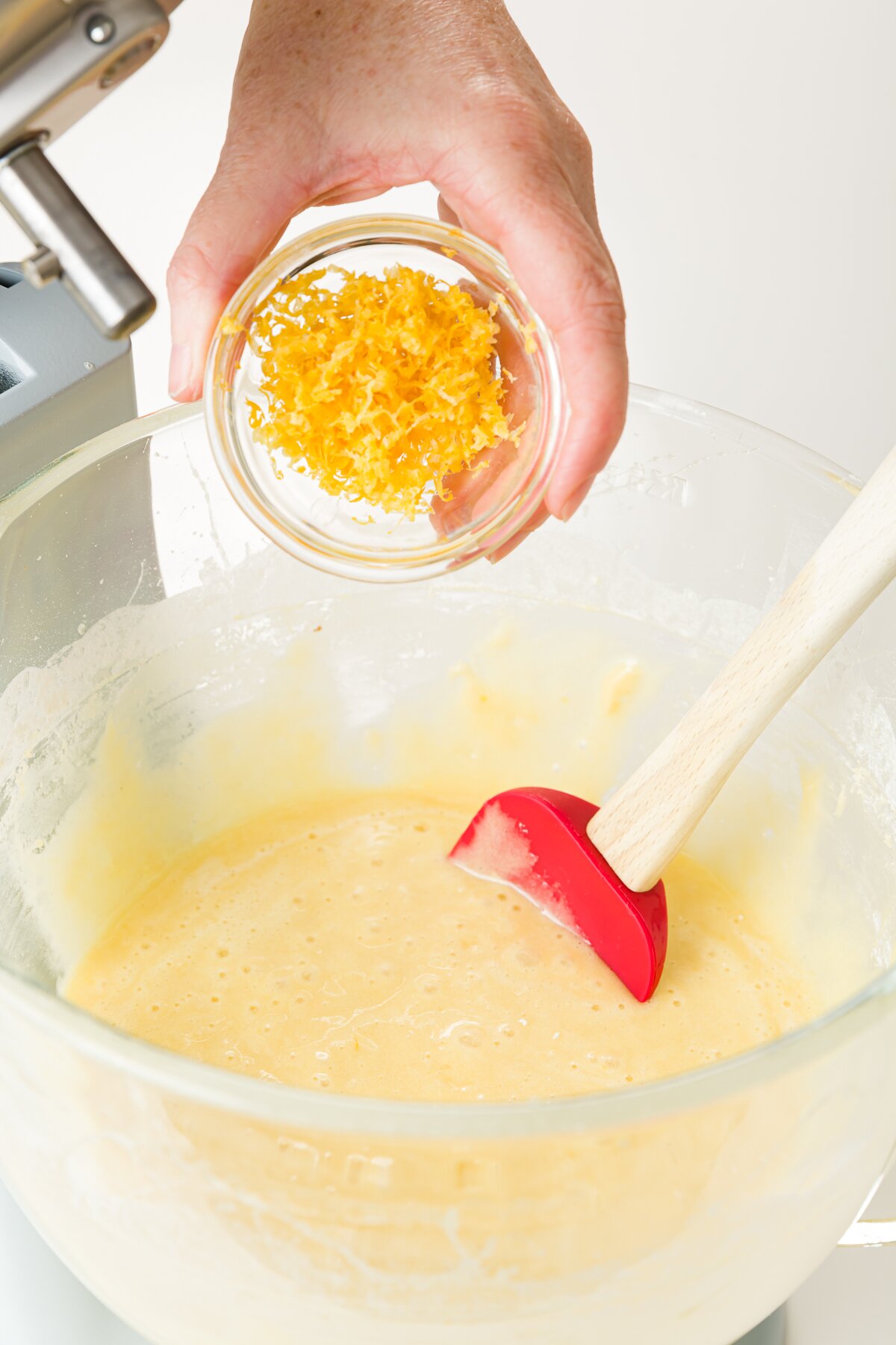 Adding lemon zest to kitchen aid bowl with batter in it