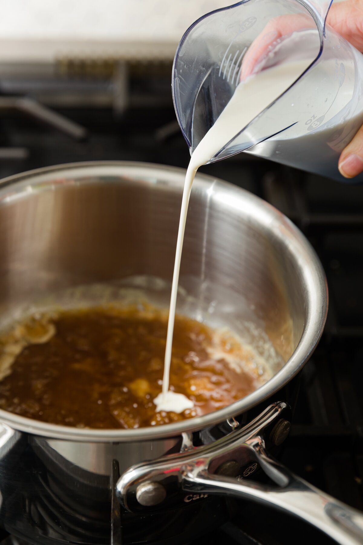 Pouring heavy whipping cream into pot of butterscotch