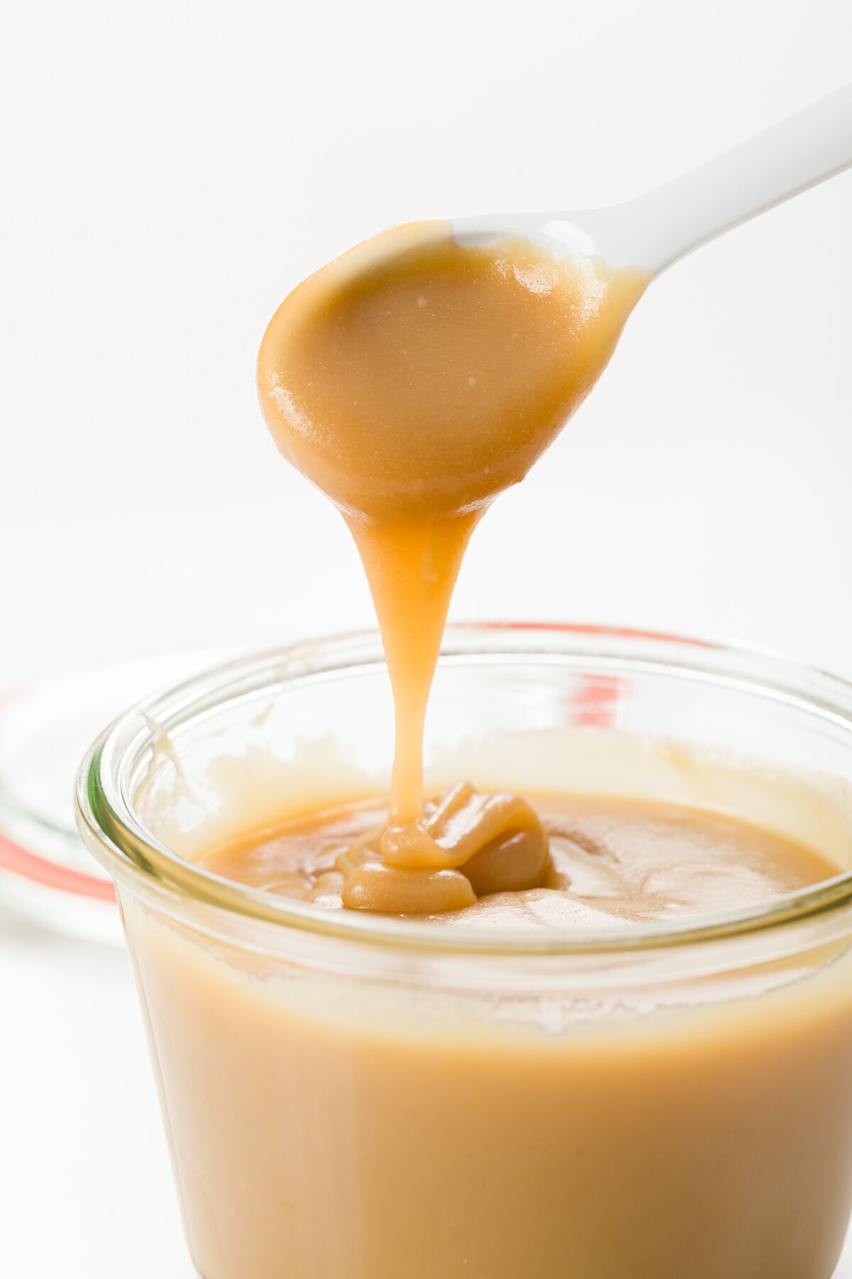 Butterscotch dripping off a spoon into a jar