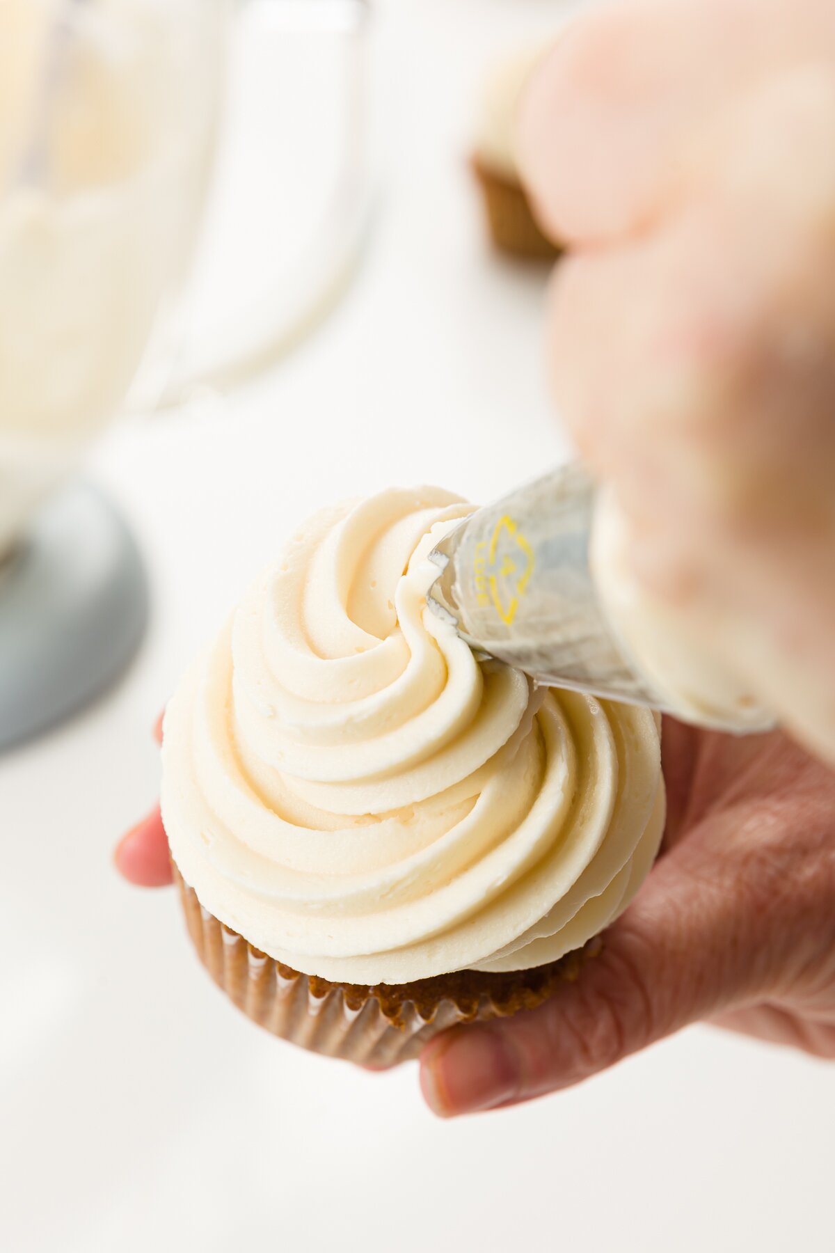 Frosting being piped onto a cupcake
